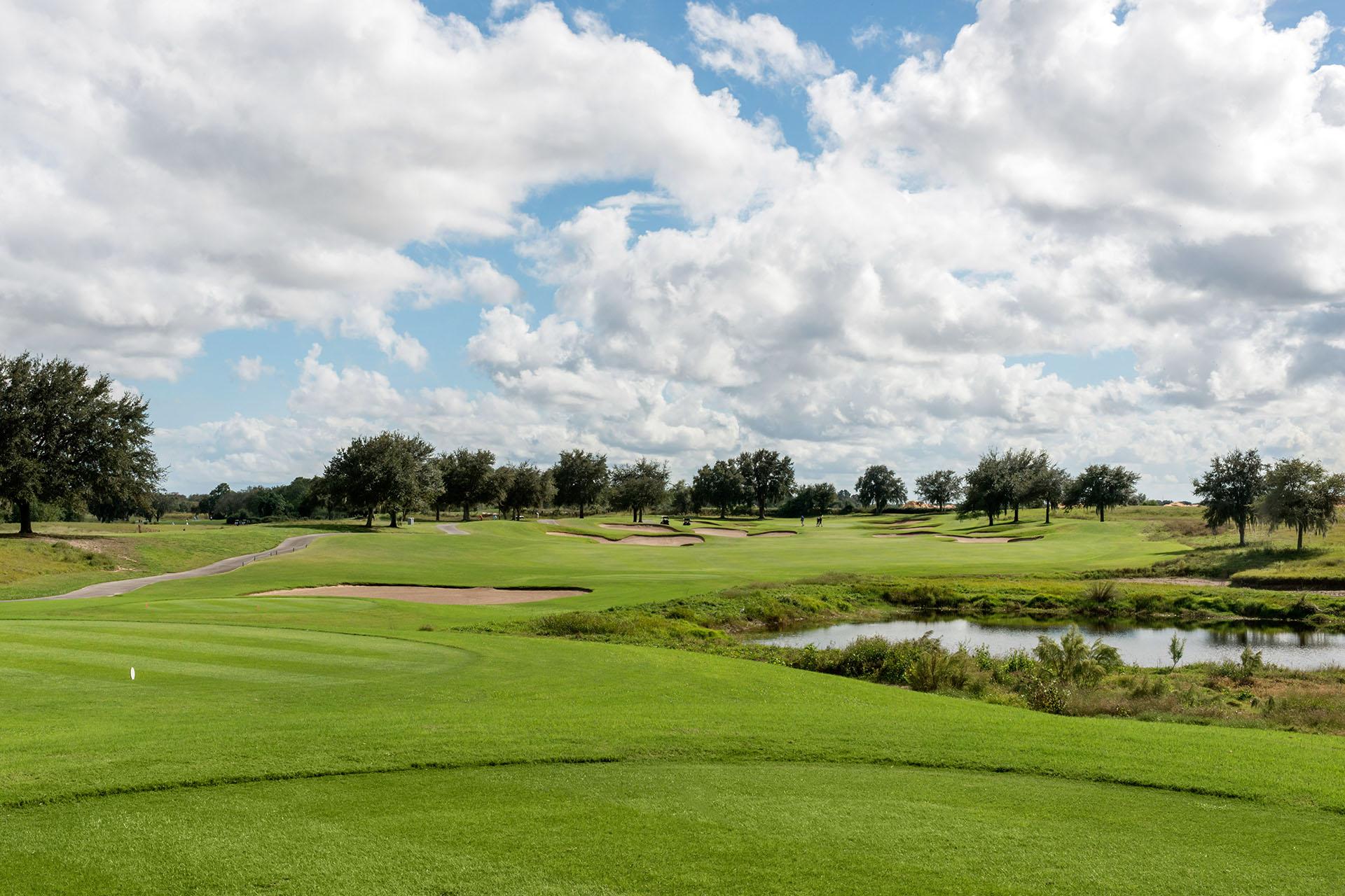 Golfers enjoying their round on the green littered with sand bunkers under cloudy skies