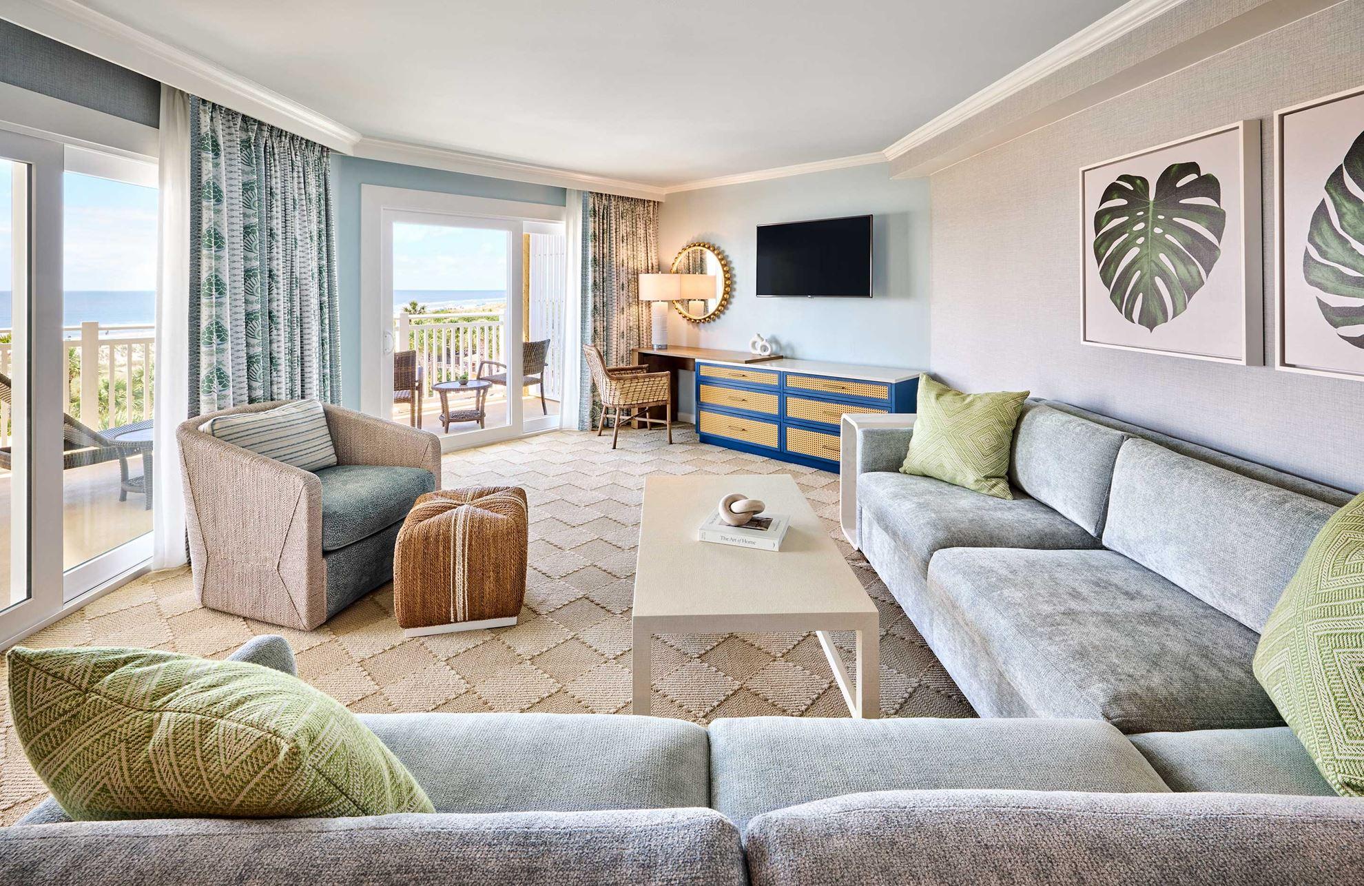 Living room as part of a suite at the resort with a large sofa, smart TV and balcony views of the beach