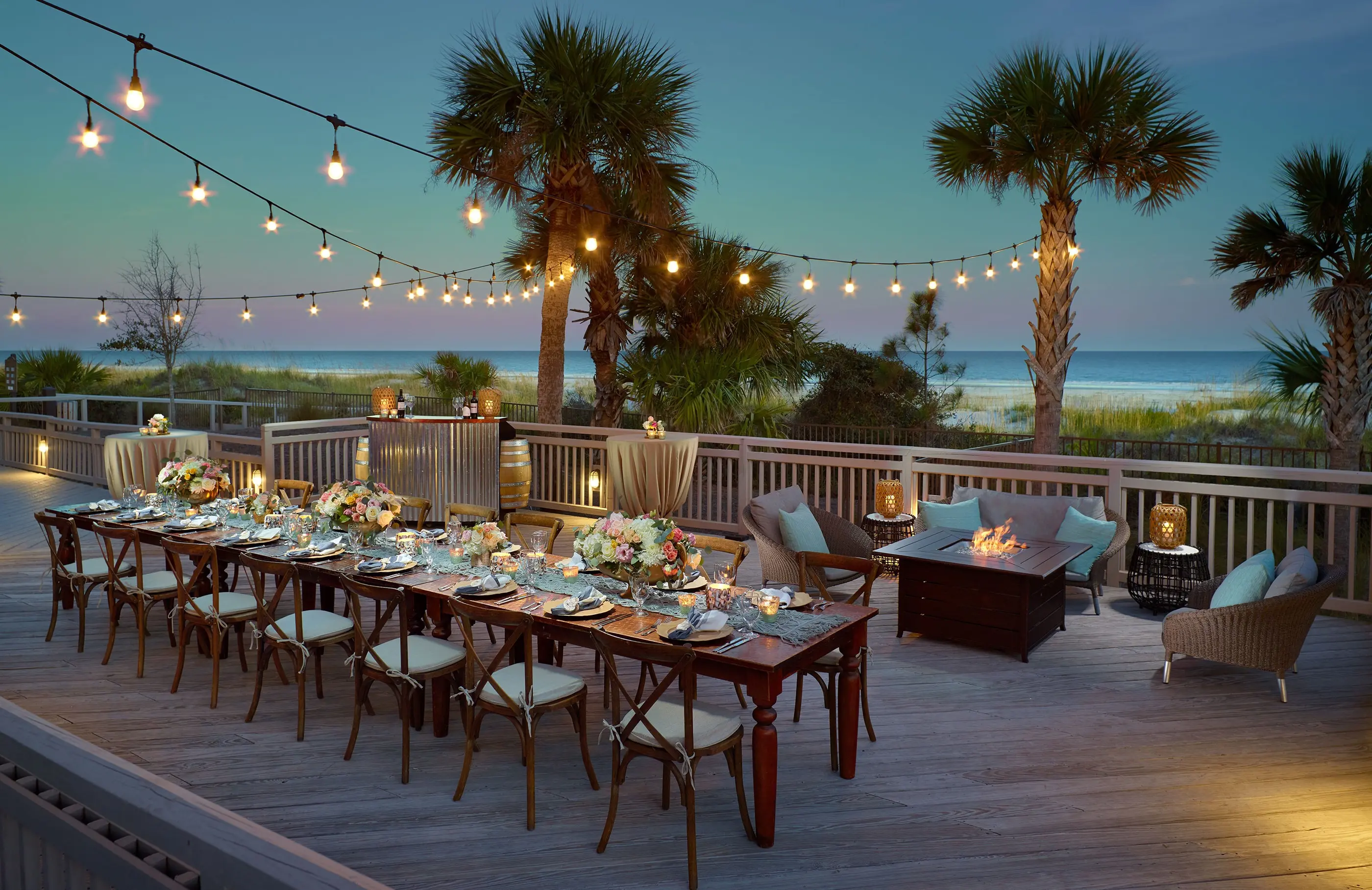 Outdoor dining table and fire pit at sunset with beach views