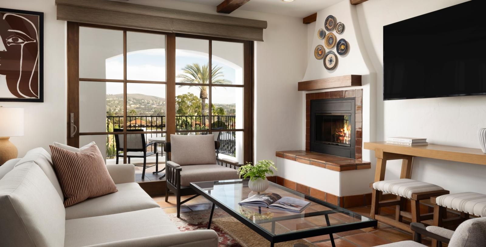 Living room as part of a sweet at the Omni La Costa Resort featuring a fire place, smart TV, sofas and a balcony with views of the resort and local town