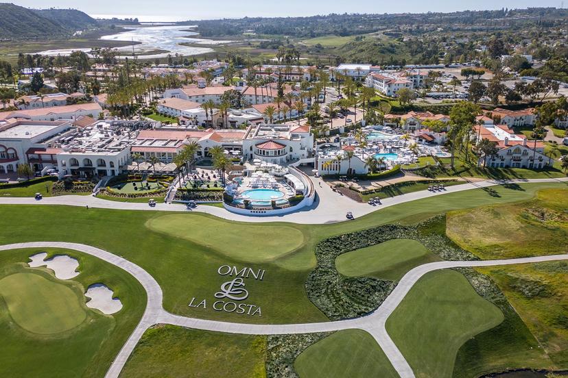 Closer birdseye view of the resort building overlooking its course with their company name and logo nestled next to a green on the course