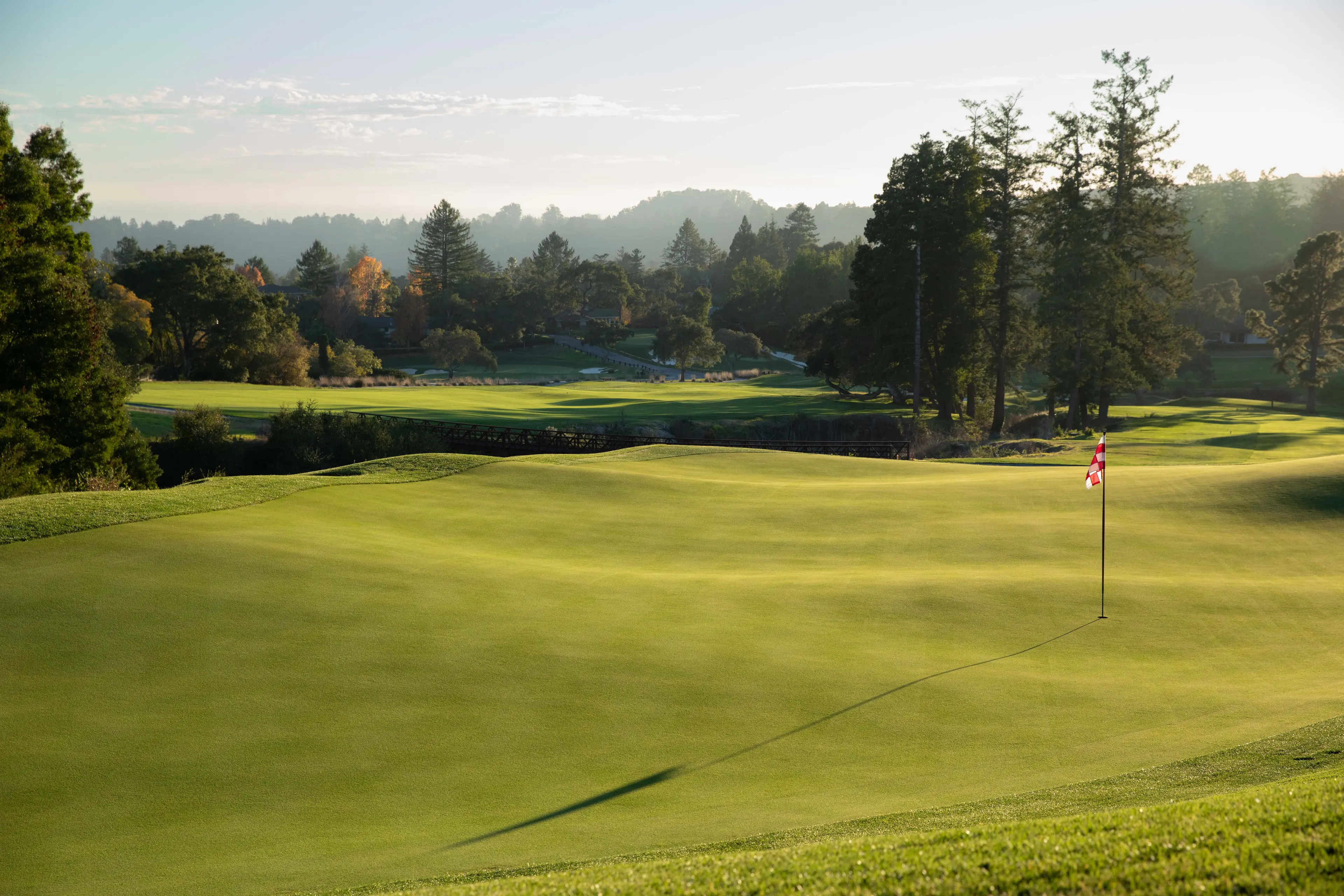 A smooth green at sunset with the flagstick shadowing on the putting grass