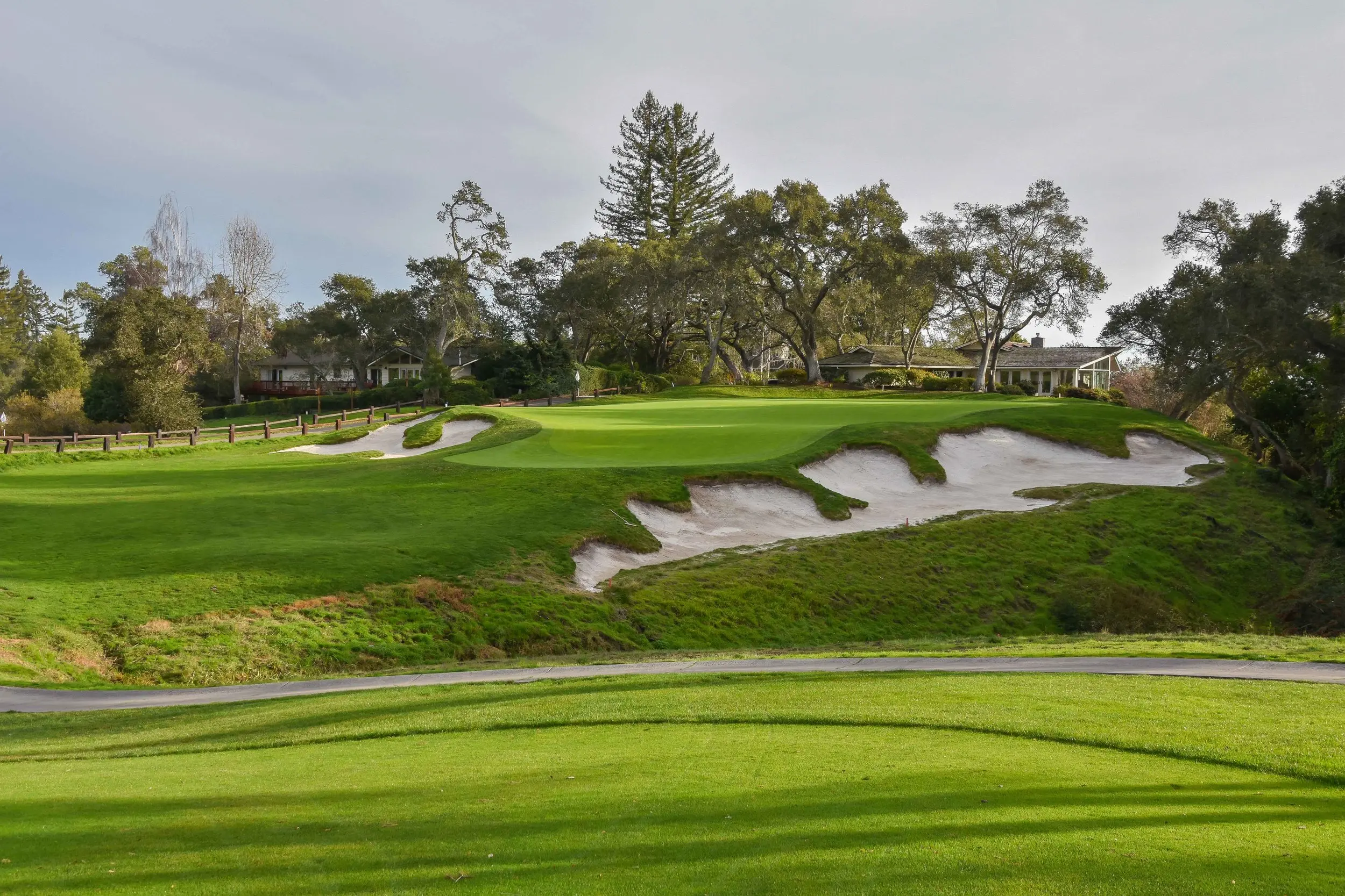 A large uniquely shaped slanted sand bunker placed next to a well maintained green
