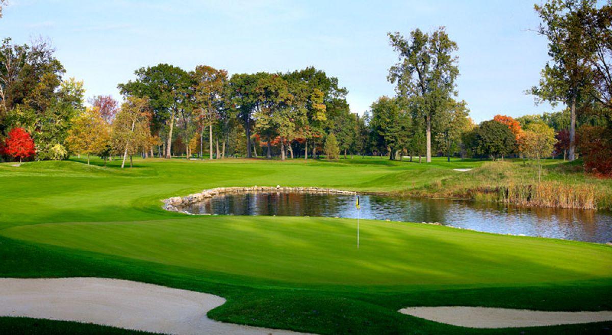 A winding fairway leading to a smooth green next to a water hazard