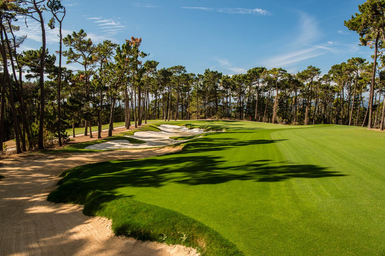 A wide fairway littered with sand bunkers leading to a well-kept green