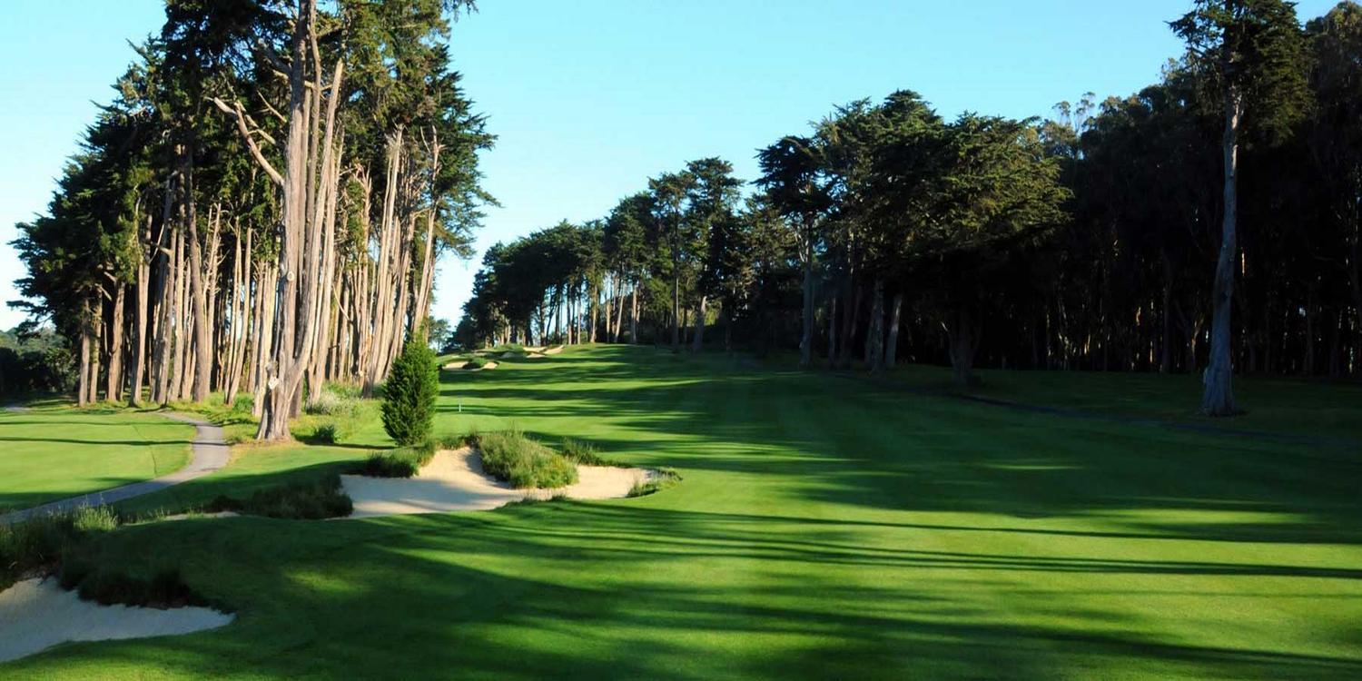 A fairway with a tree line and sand bunkers