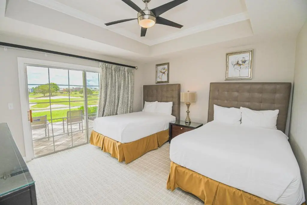 Double bed and single bed room at the resort with patio views of the course and an outdoor seating area