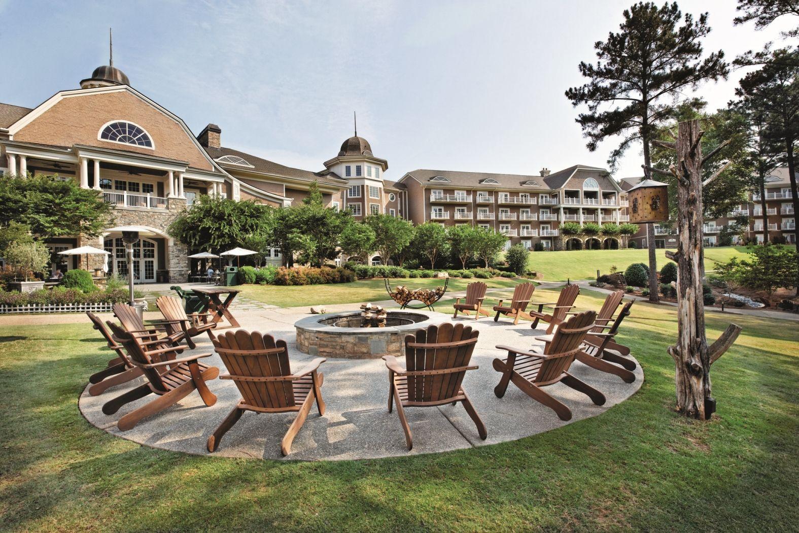 Outdoor seating area at the hotel surrounding a fire pit with the building towering over