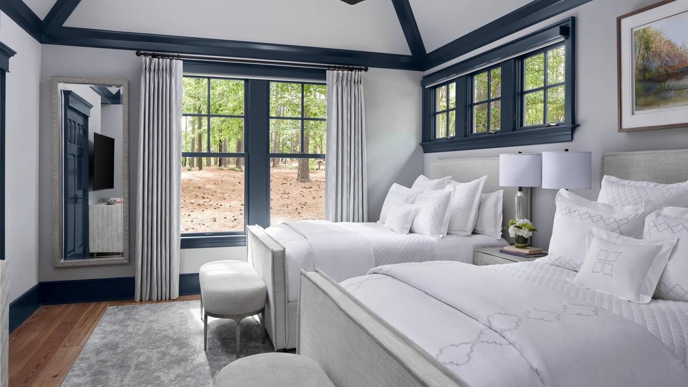 Twin double bed suite at the hotel following a white, grey and blue design featuring a window view of nature