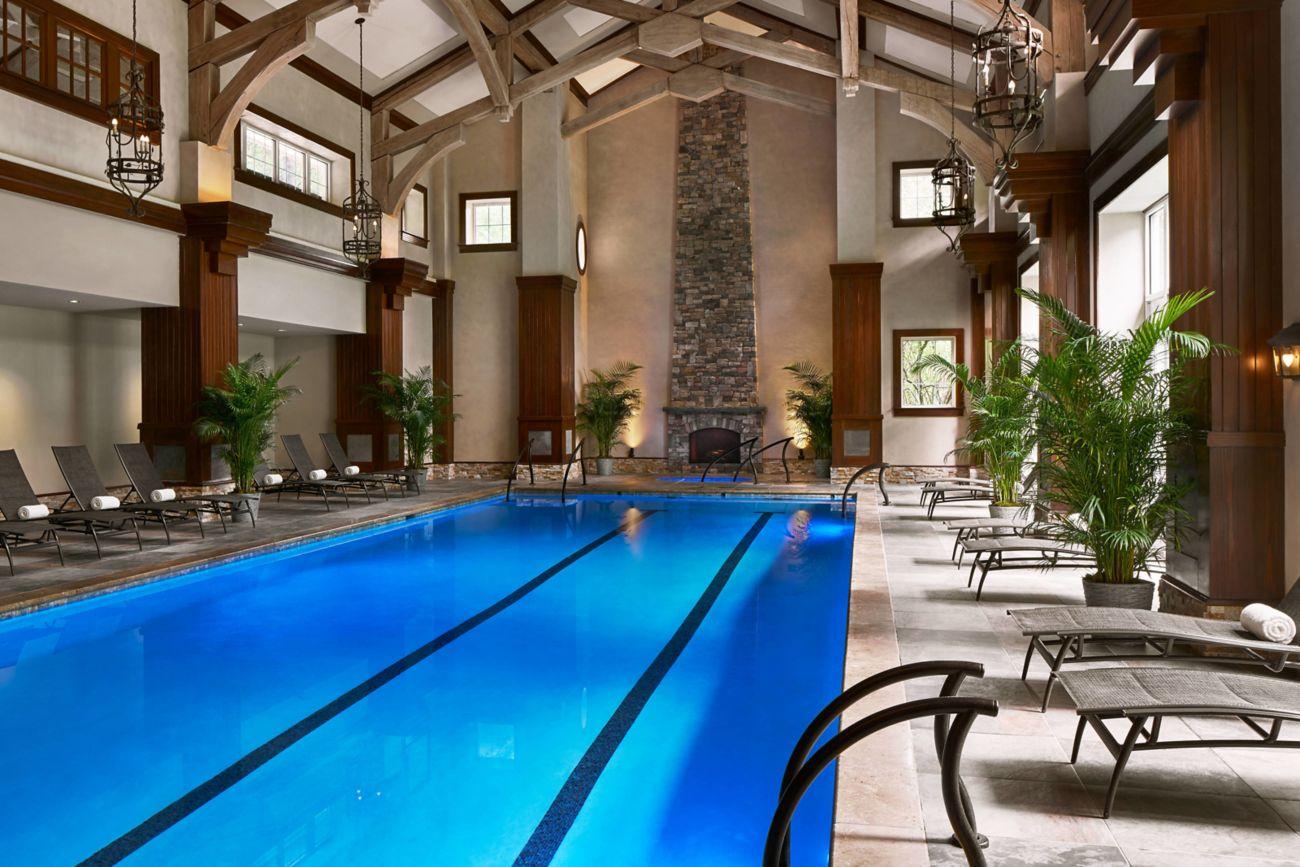 Indoor swimming pool at the hotel with a grand stone and wood design surrounded by sunbeds