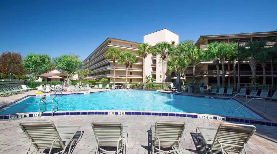 Guest at the Rosen Inn hotel enjoying their day by the pool with the building in the back