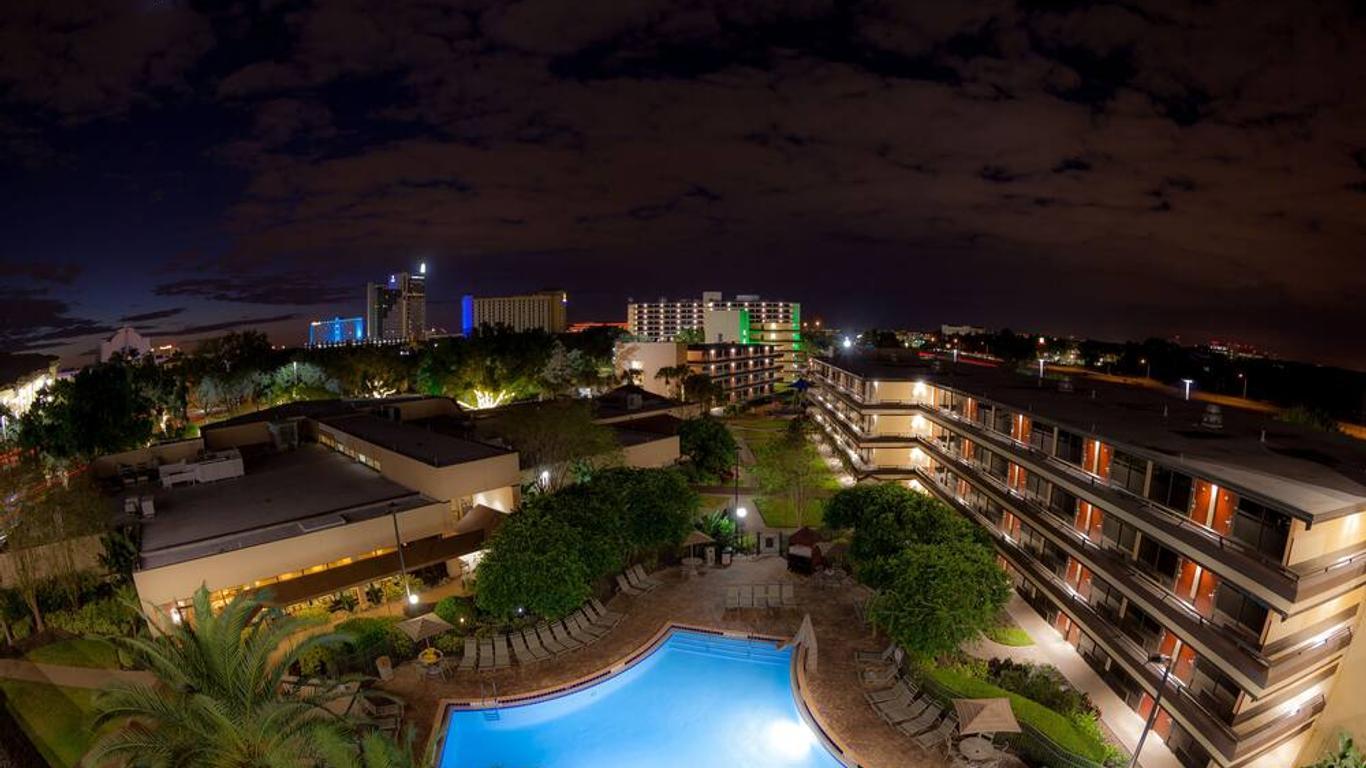 Overhead panoramic view of the hotels pool and building at night time being illuminated by poolside lights