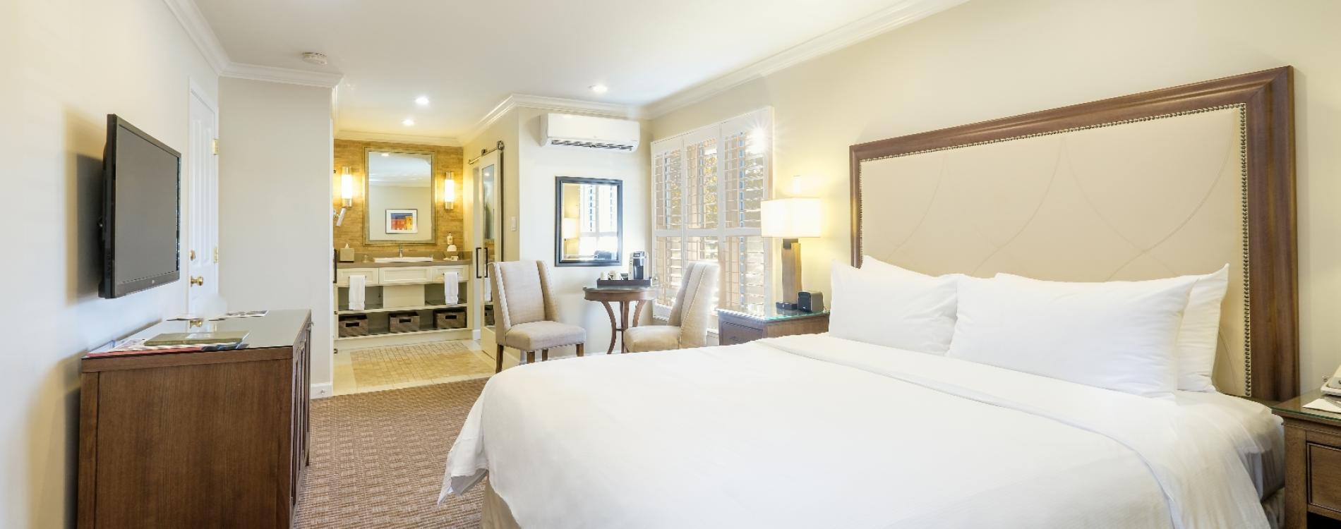 A double bed room with an open floor design leading to the bathroom