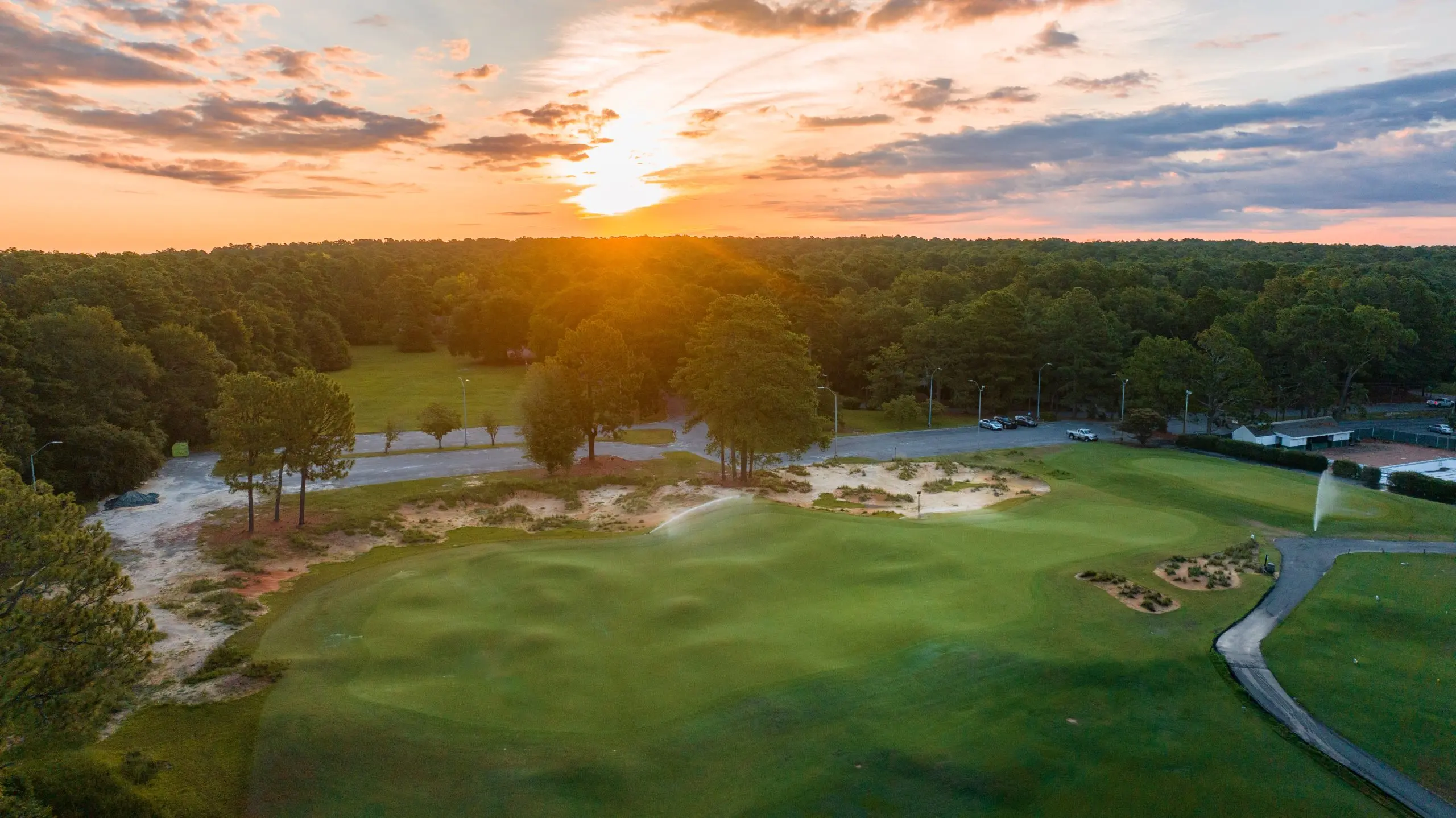 A stunning sunrise over the Southern Pines Golf Club, casting golden light across the pristine green.