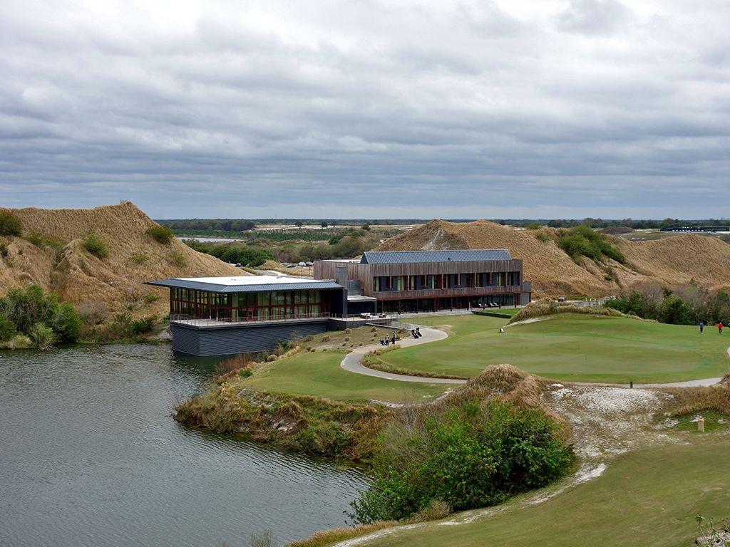 Wide angle view of golfers enjoying their round on manicured green with the clubhouse towering over