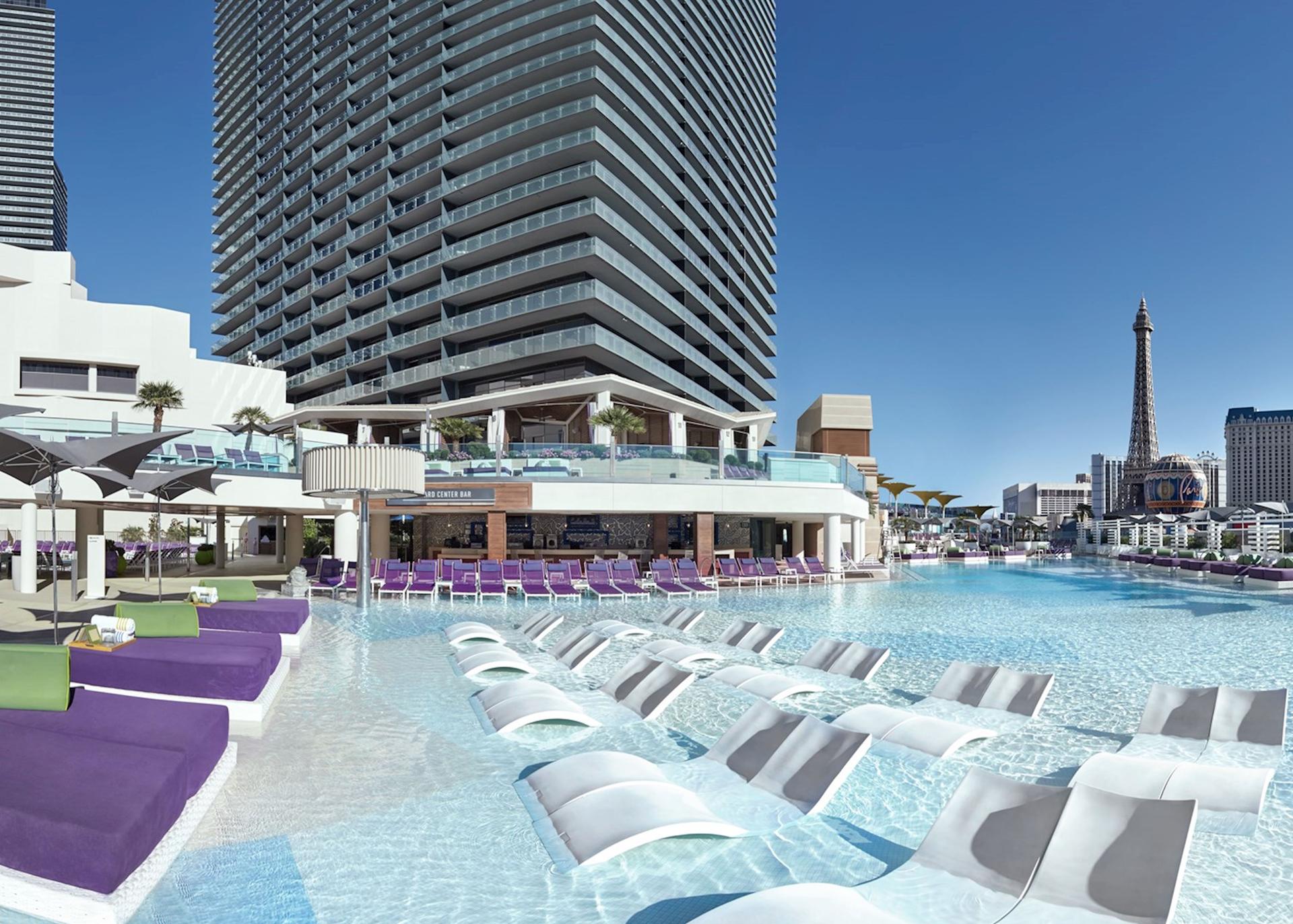 Panoramic view of the hotel building towering over their outdoor swimming pool