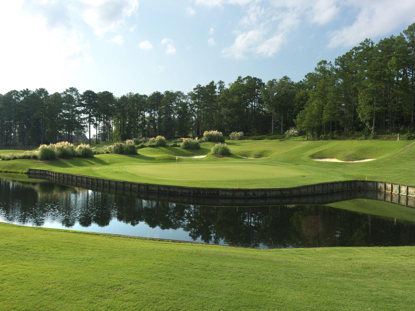 A smooth green elevated from water feature by a wooden wall