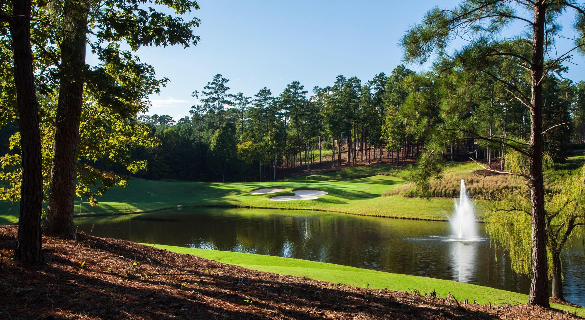 A large water hazard with a fountain feature placed next to a green