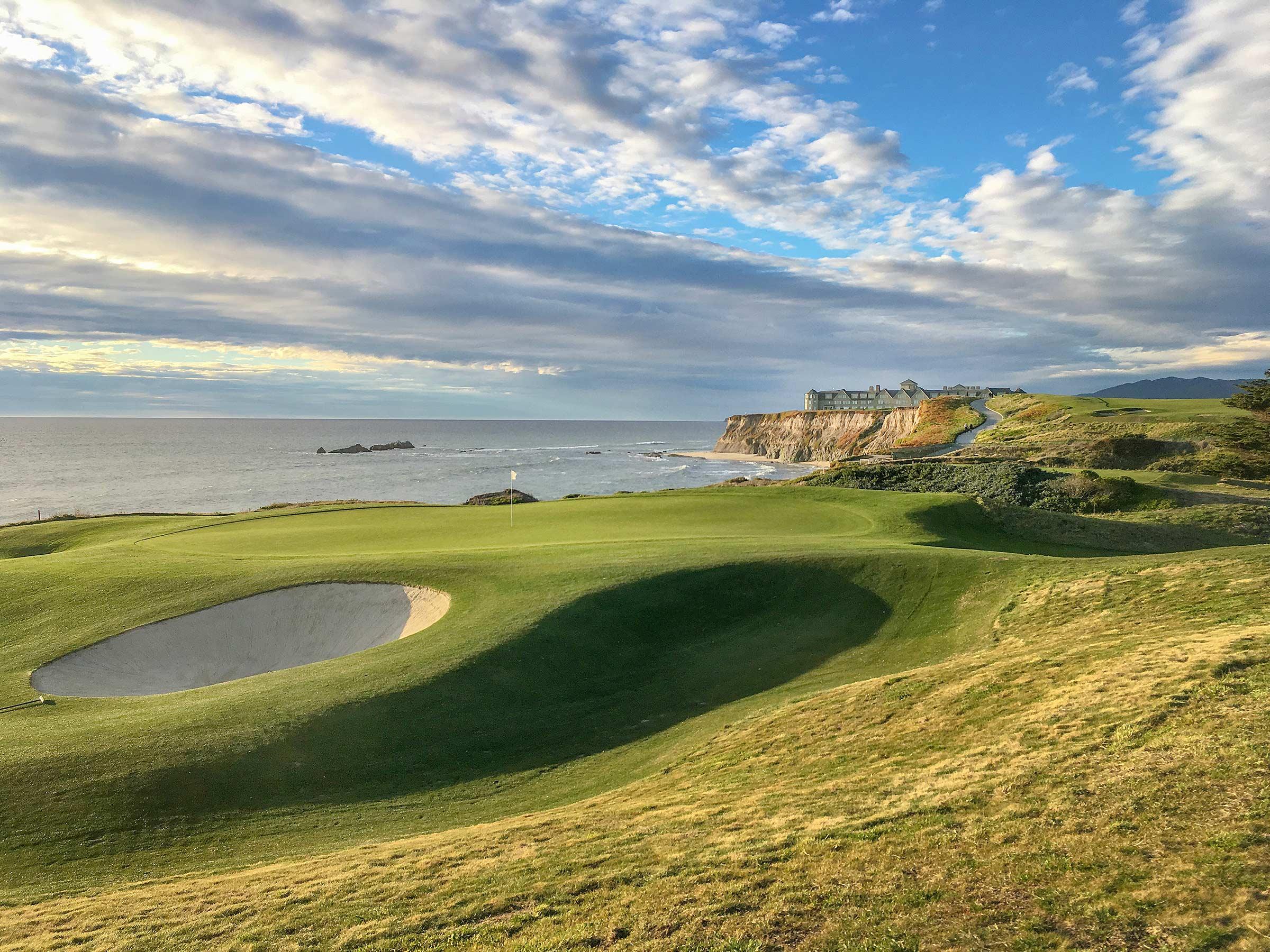 A elevated green surrounded by sand bunkers with coastal views