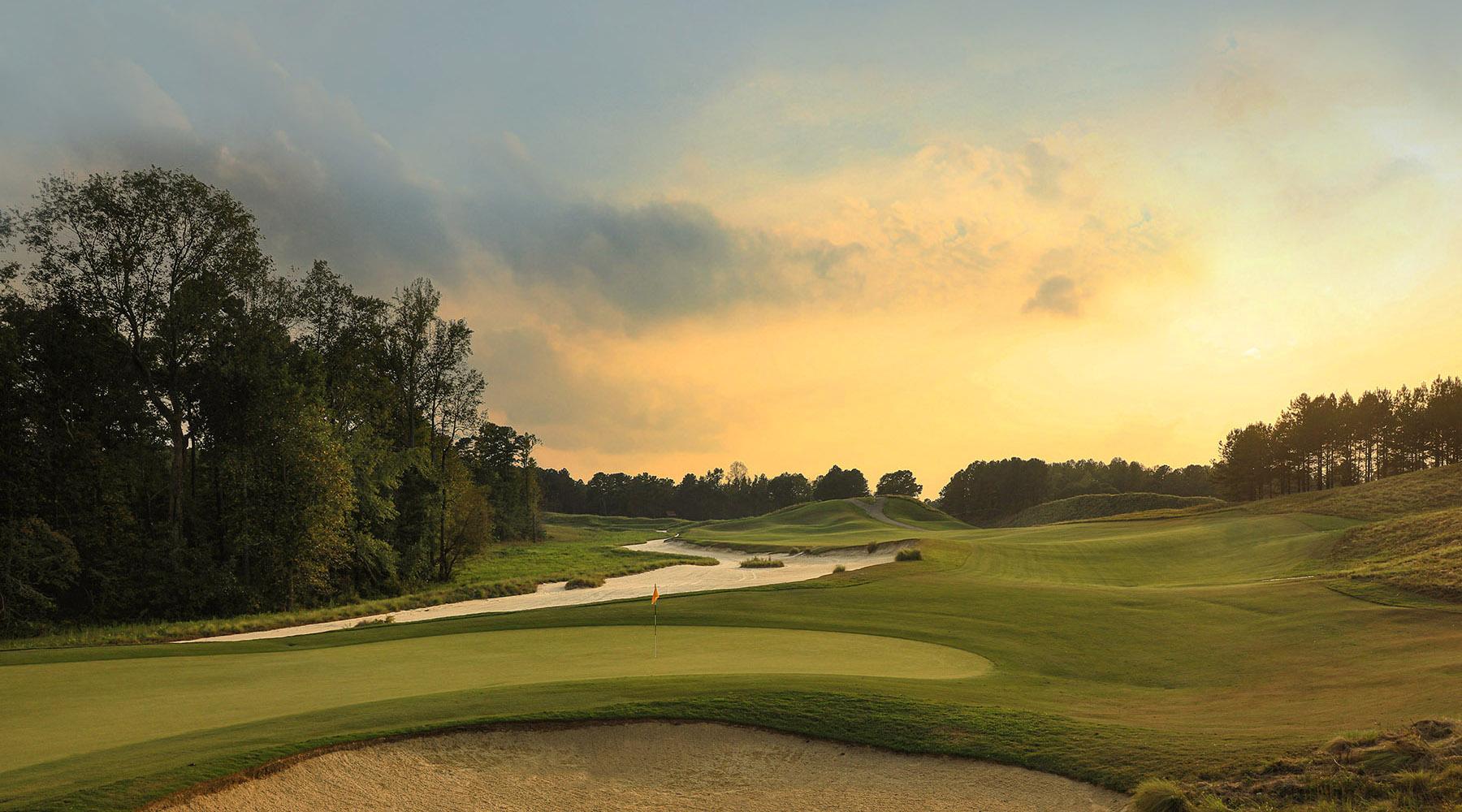 Sun setting over a winding fairway which leads to a smooth green on the Tobacco Road course