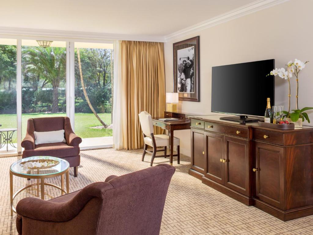 Sitting room in a suite with flat screen TV and a patio that leads to a nice garden