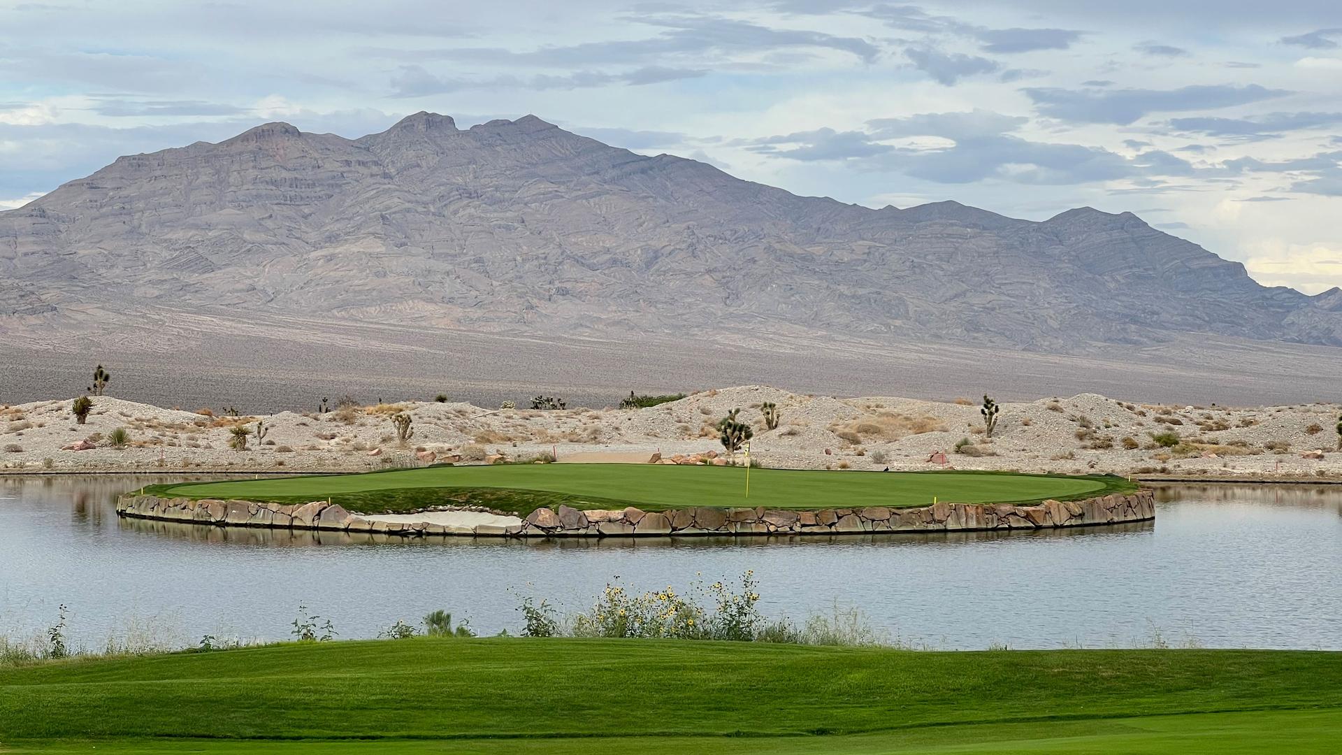 An island green surrounded by a stone wall elevating it from the water hazard
