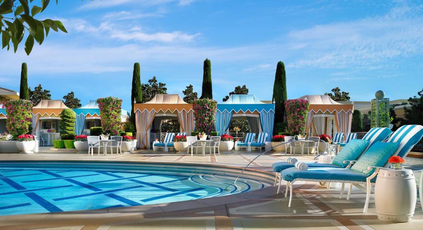 Outdoor swimming pool surrounded by sun beds under blue skies