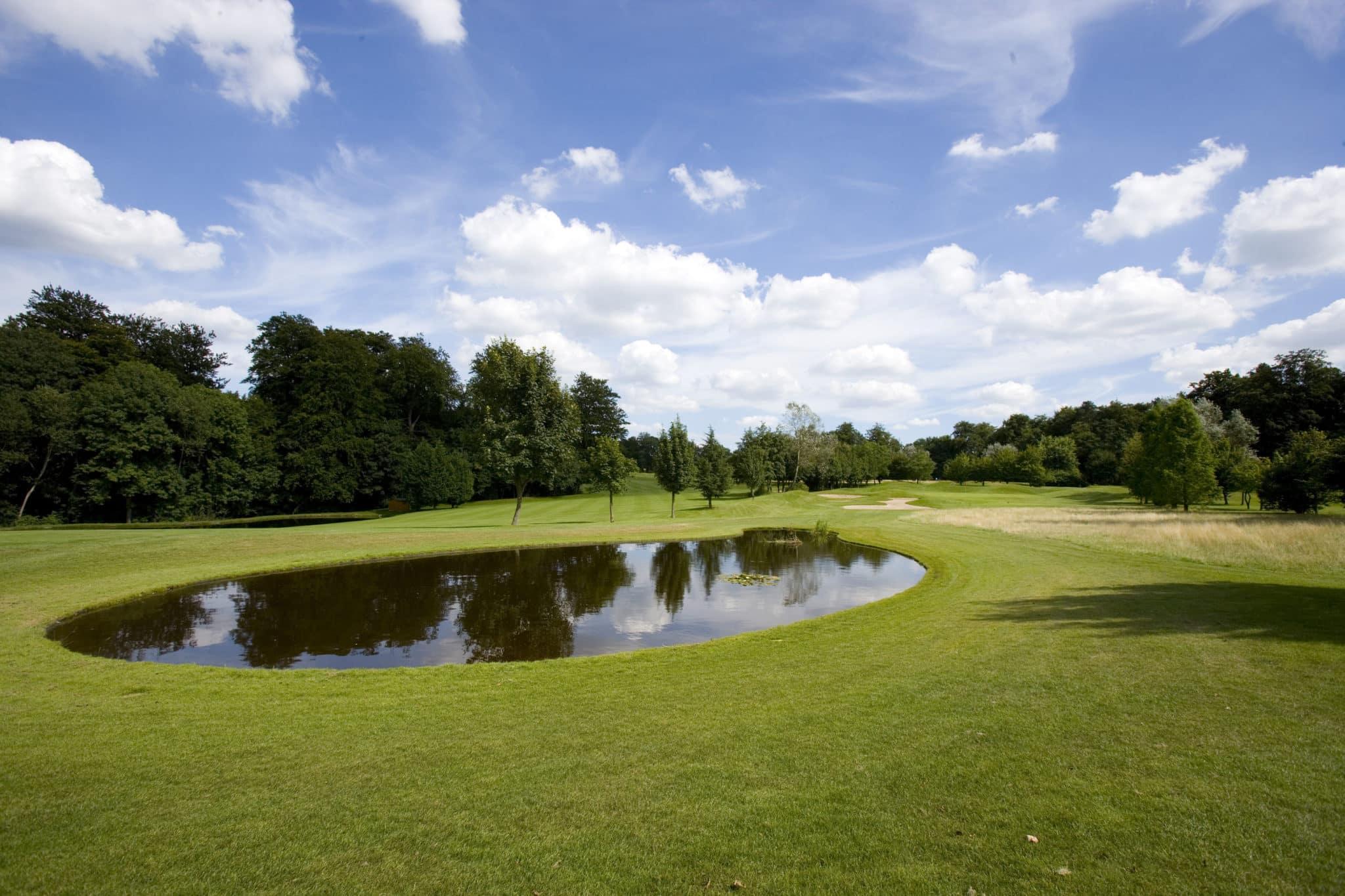 A water hazard placed in the centre of a wide fairway with surrounding trees