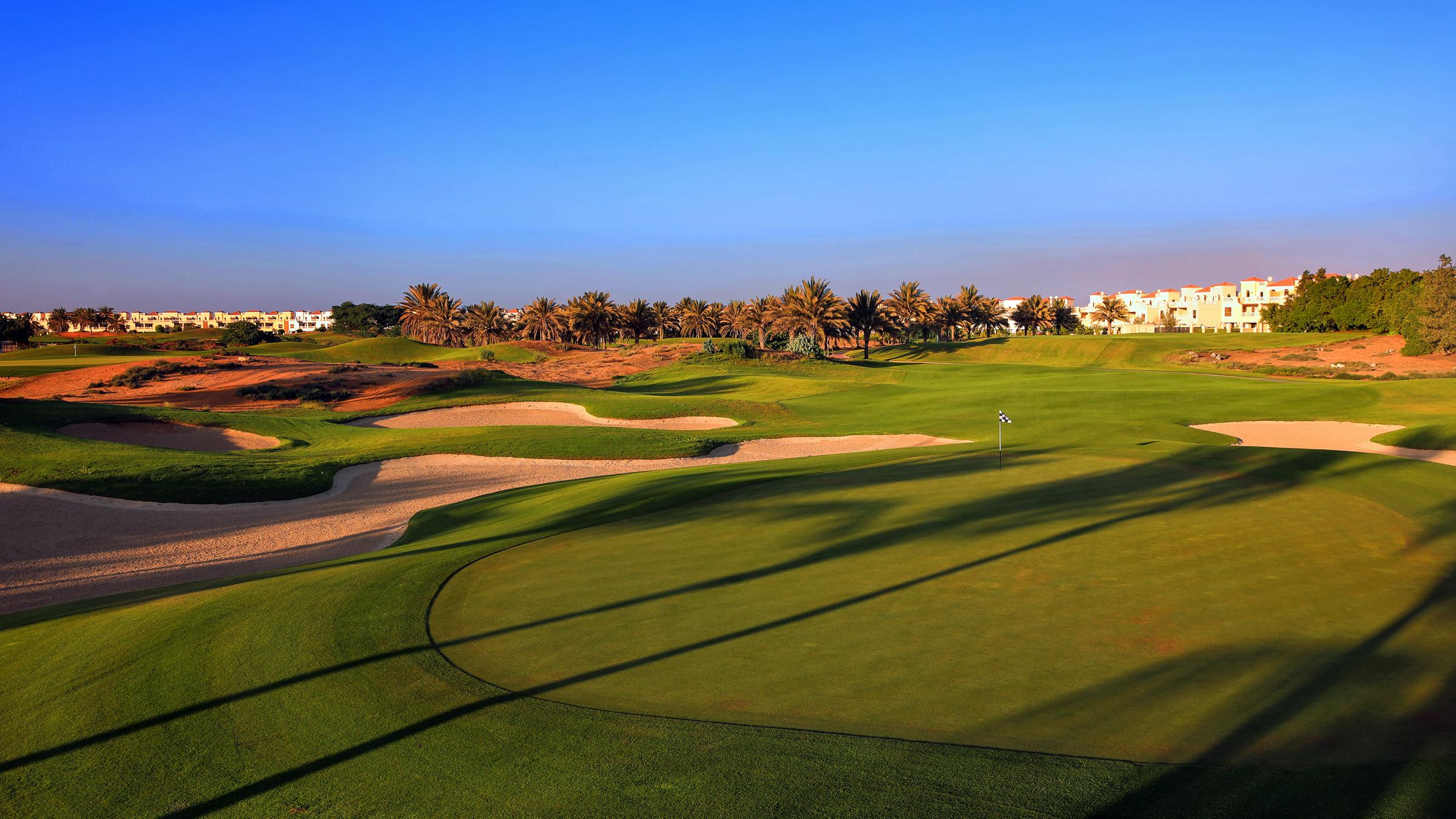 A smooth green surrounded by sand bunkers under clear blue skies