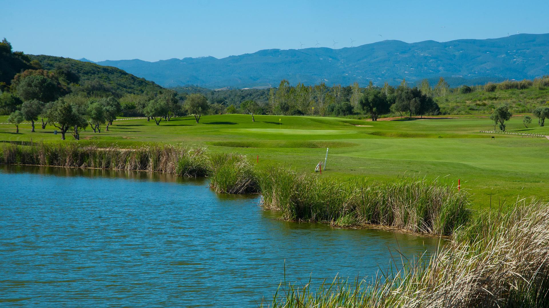Water hazard in the foreground with the fairway and bunkers on the right leading to the green