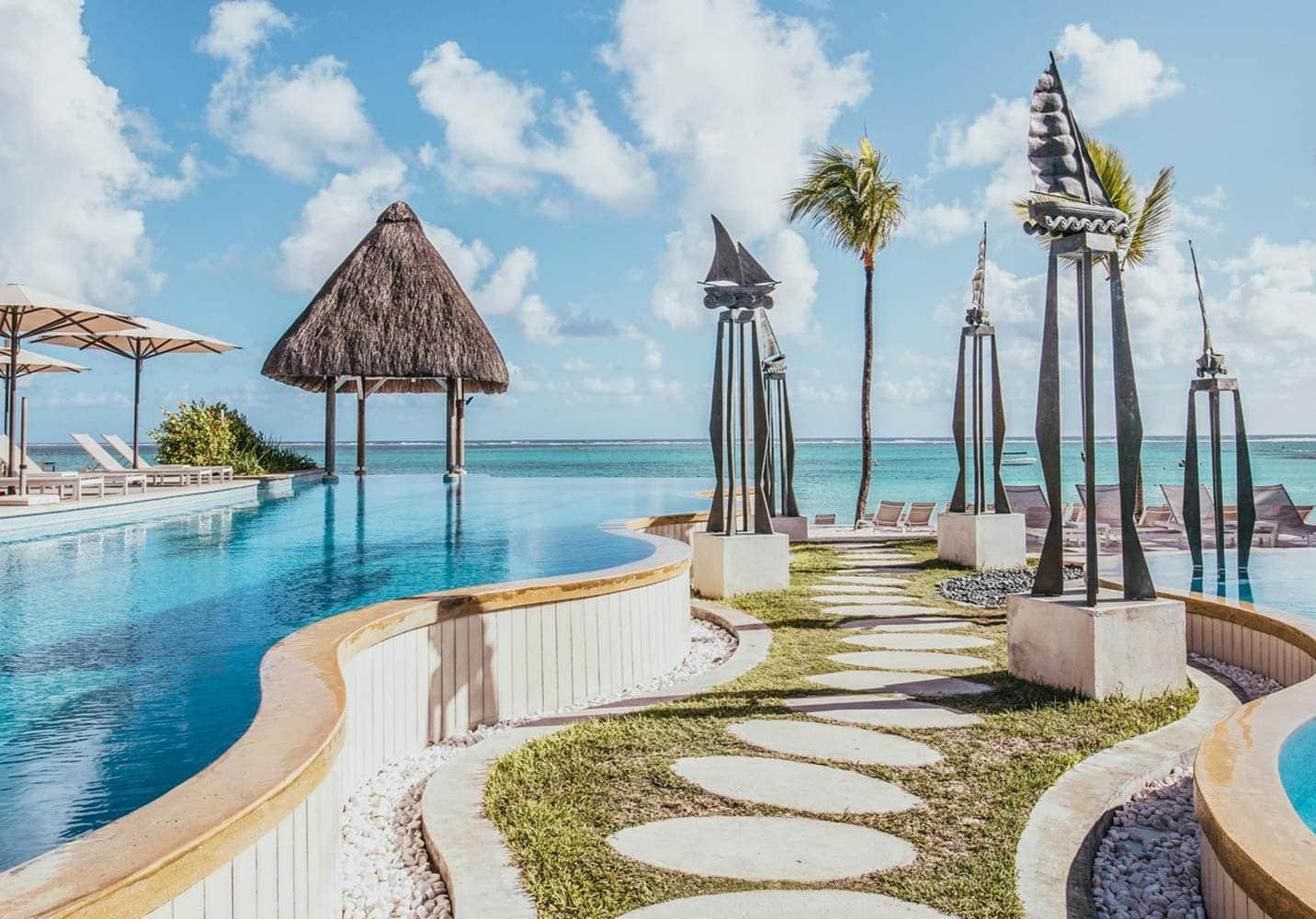 A stepping stone walkway sandwiched between two parts of the swimming pool leading to a sunbed section