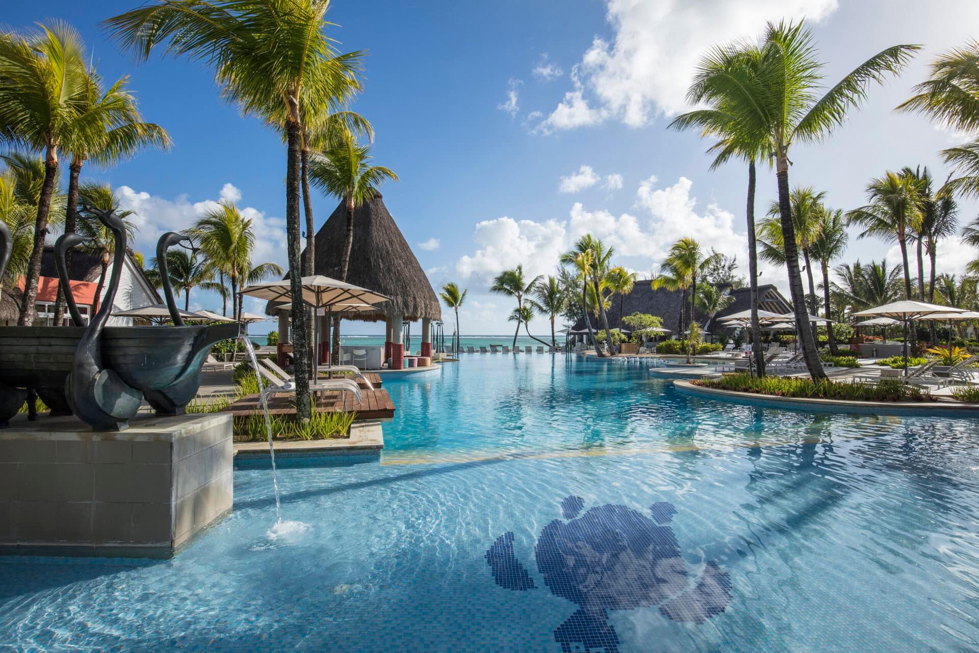 An outdoor swimming pool surrounded by sun beds and palm trees