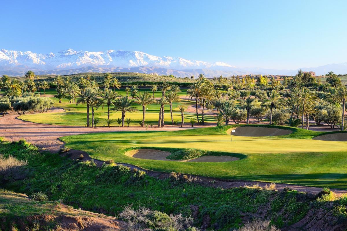 A well maintained green surrounded by sand bunkers with mountain views