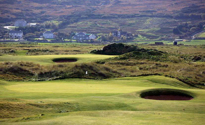Wide angle shot of the greens with surrounding bunkers and long grass on the landscape