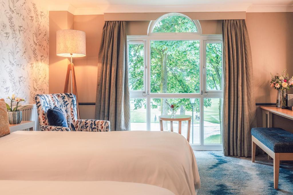 Grand window of a twin occupancy room looking out onto the on sight course with a seating area and vanity table