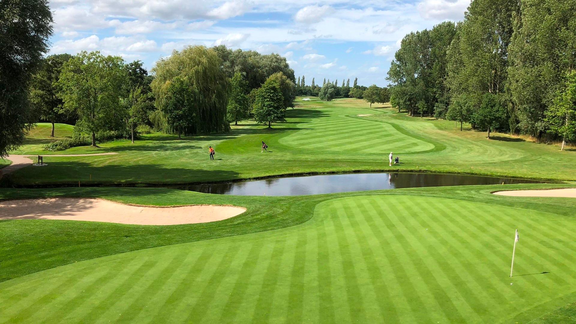 Golfers enjoying their round on wide fairways and smooth greens being separated by a water hazard