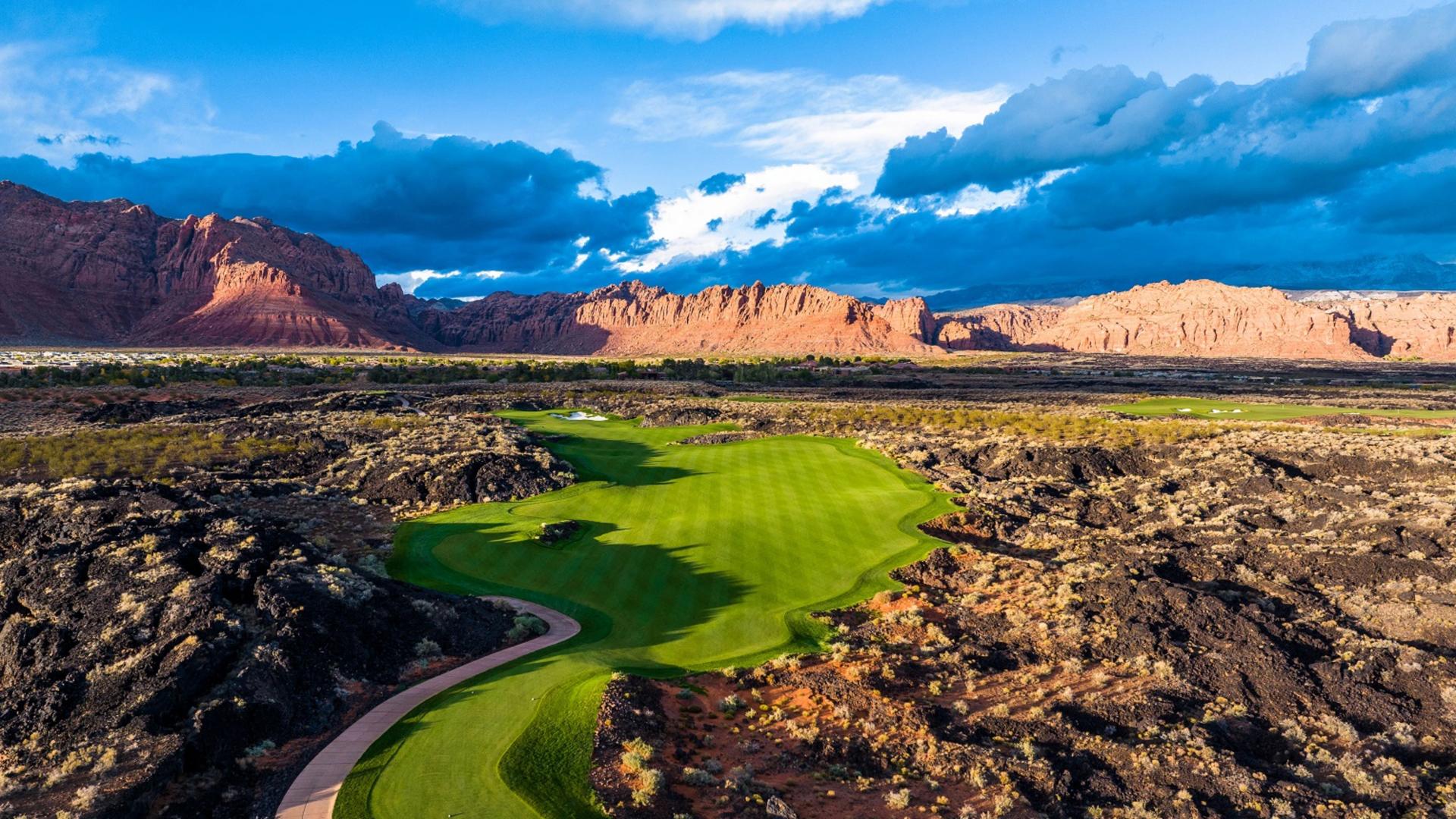 A wide well-maintained fairway surrounded by a rocky rough