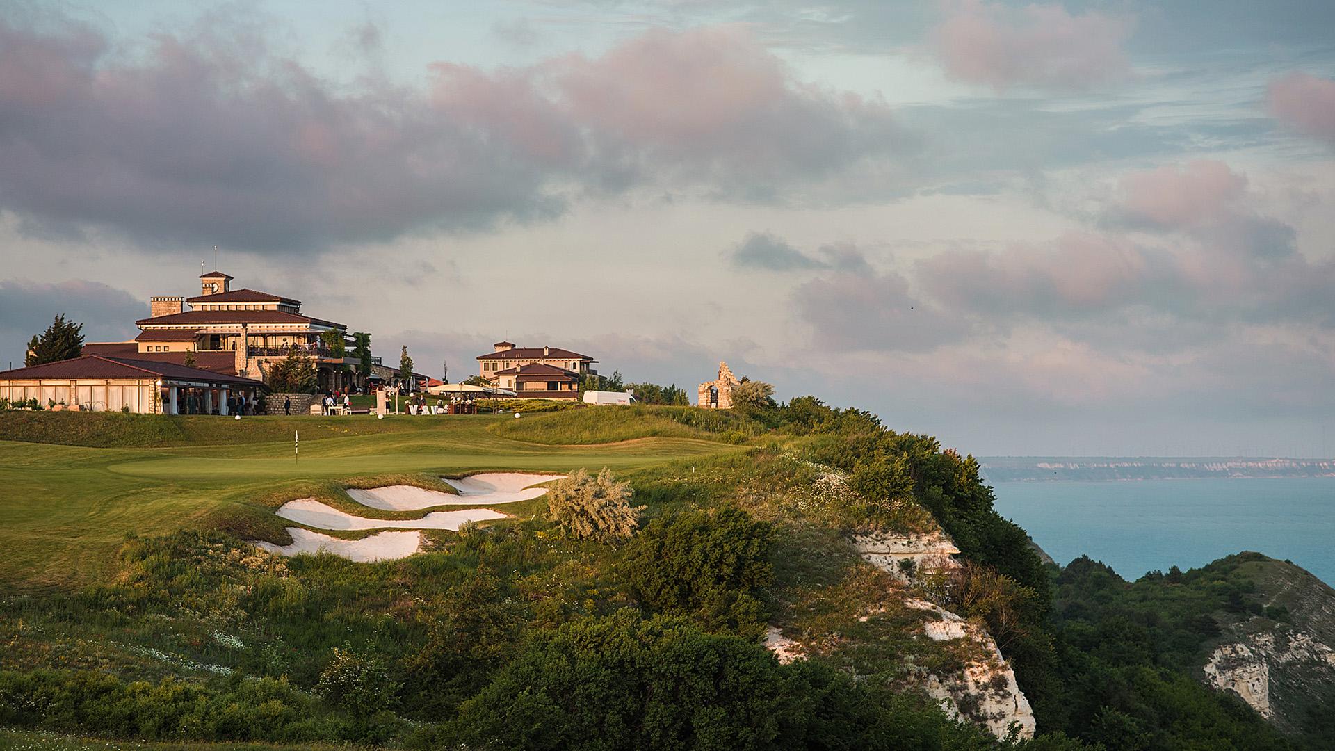 Panoramic view of the populated clubhouse over looking a green with strategically placed sand bunkers
