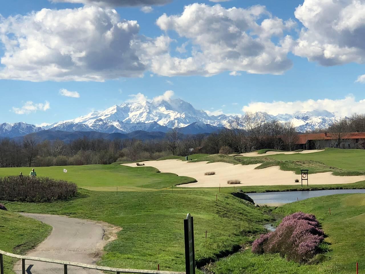 A large sand bunker and rolling dunes on the course with ice top mountain views