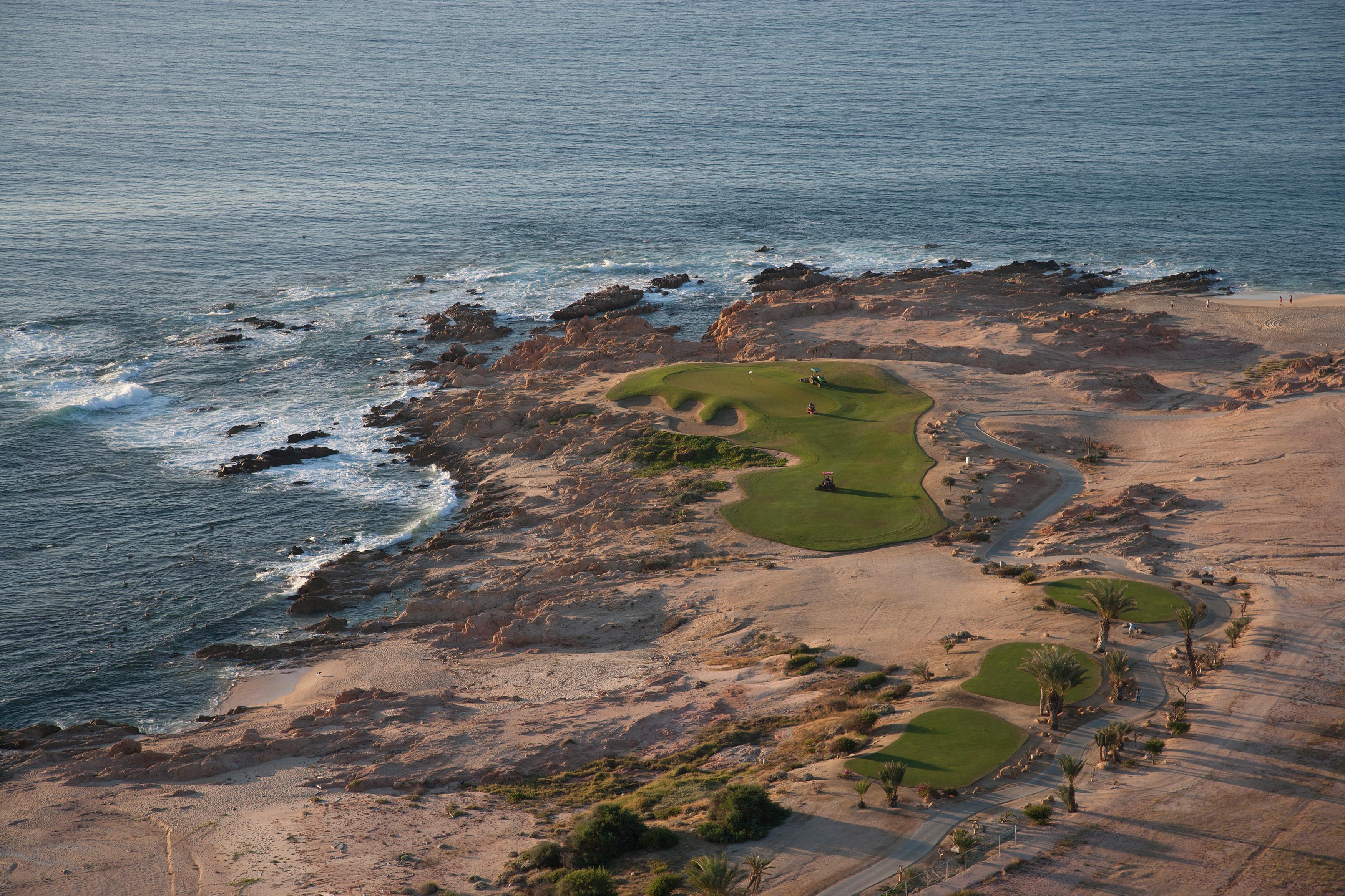 Overhead view of golfers enjoying their round on a smooth green strategically placed next to the coast
