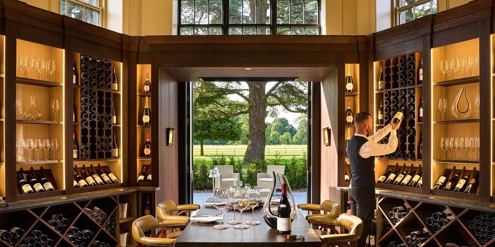 A luxurious wine room with shelves of wine bottles and elegant glassware.
