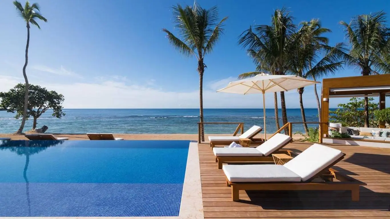 Infinity pool at the resort with sunbeds leading to the beach