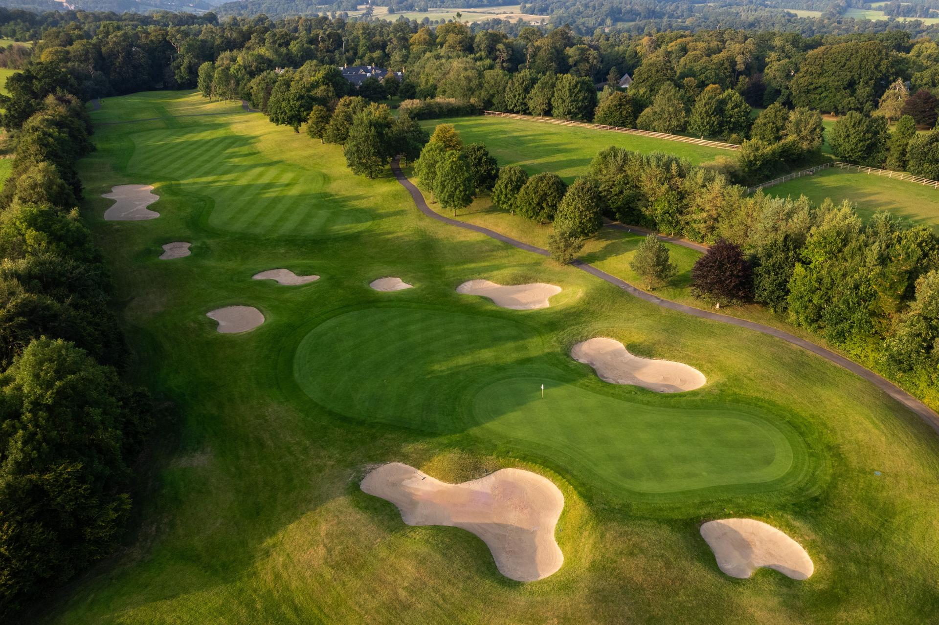 A tree-lined fairway with perfectly placed bunkers creating a strategic challenge for golfers.