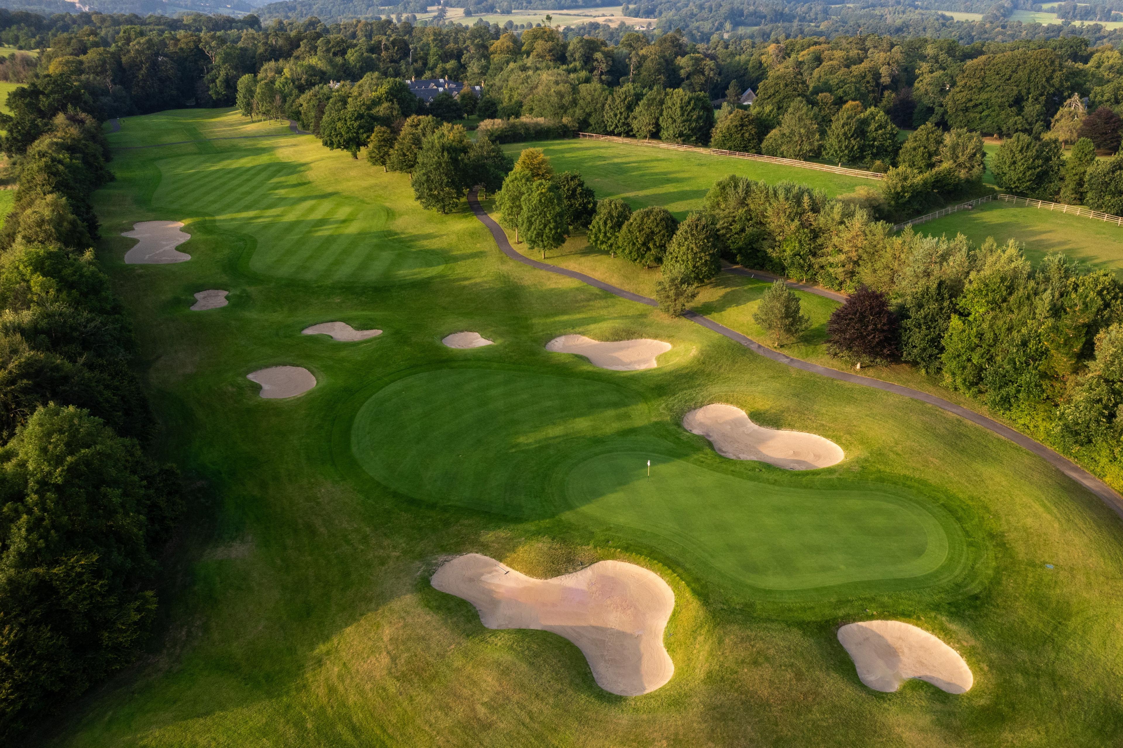 A tree-lined fairway with perfectly placed bunkers creating a strategic challenge for golfers.