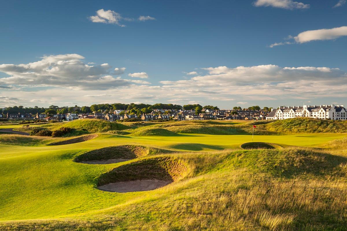 The historic clubhouse overlooking a pristine green with traditional links features.