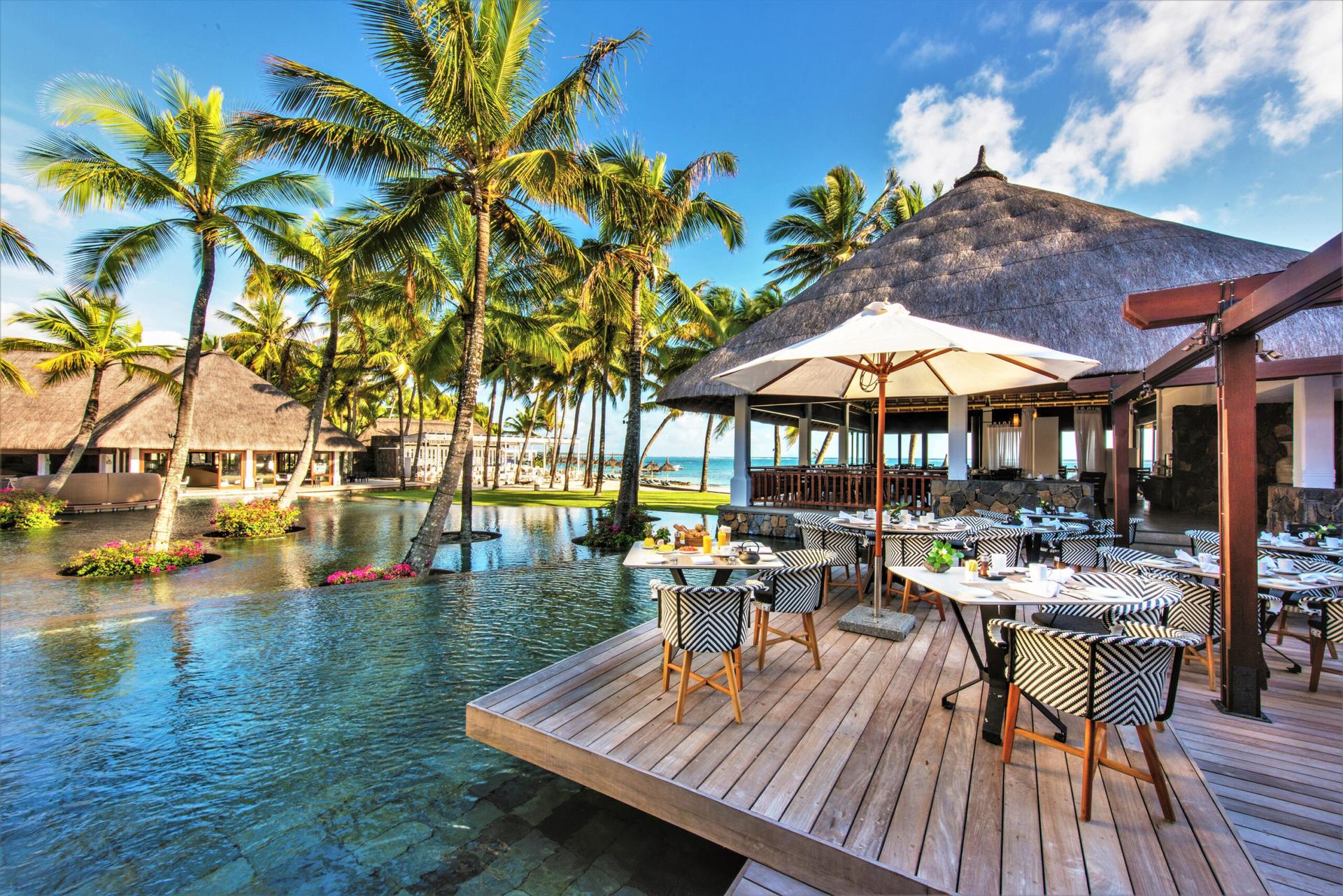 A poolside dining area nestled with palm trees and sea views