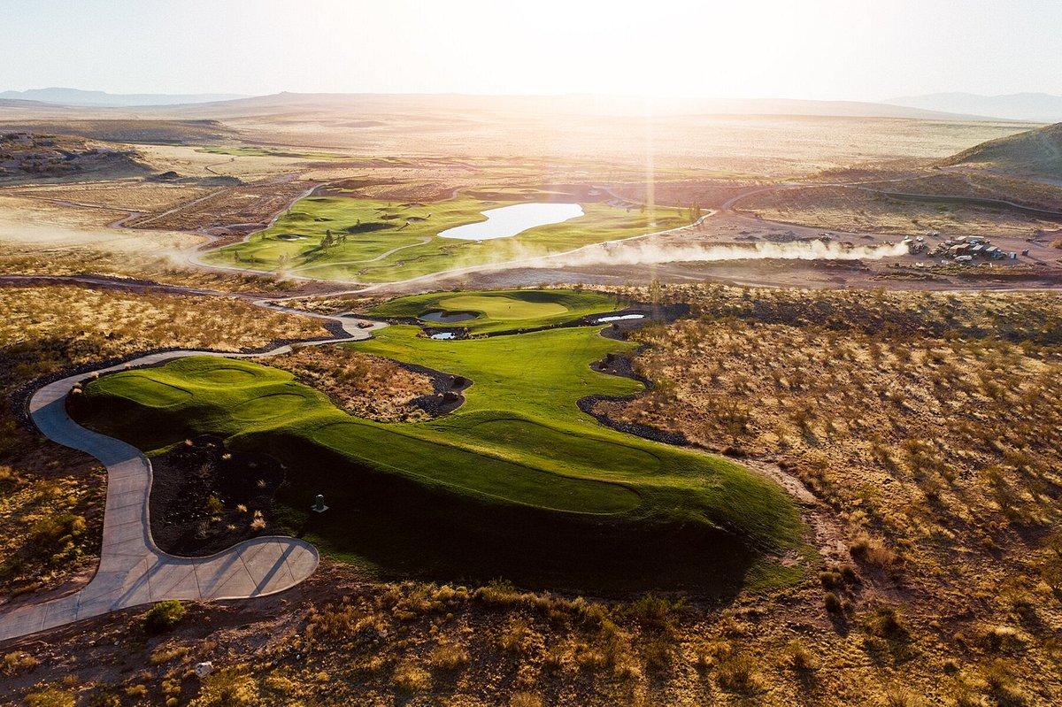 A sprawling desert course with winding fairways and bright sunlight.