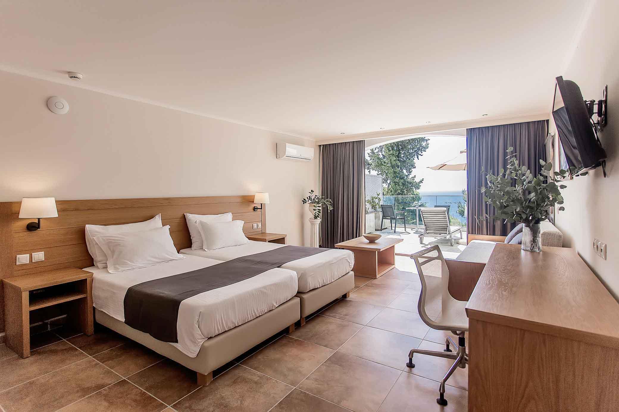 Twin bed room at the hotel with a balcony equipped with its own sunbed and umbrella