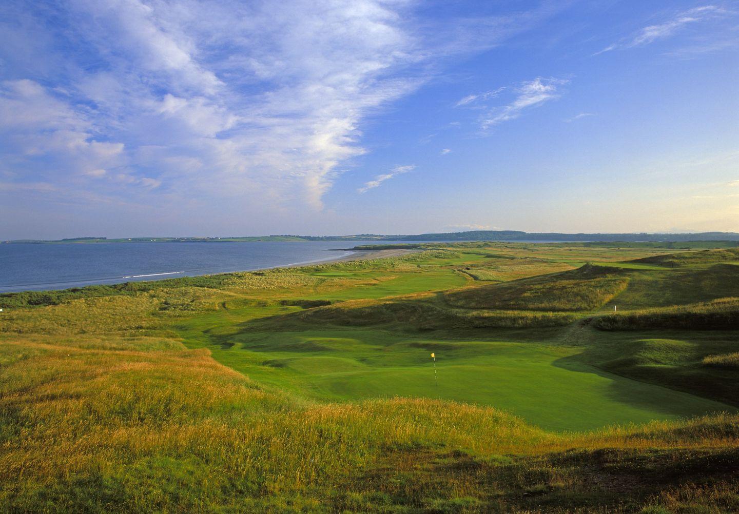 Birdseye view of the lush greens and wide fairways with a beautiful blue sky overlooking the course