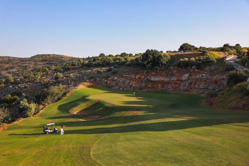 A golfer plays a shot near a dramatic cliffside green.